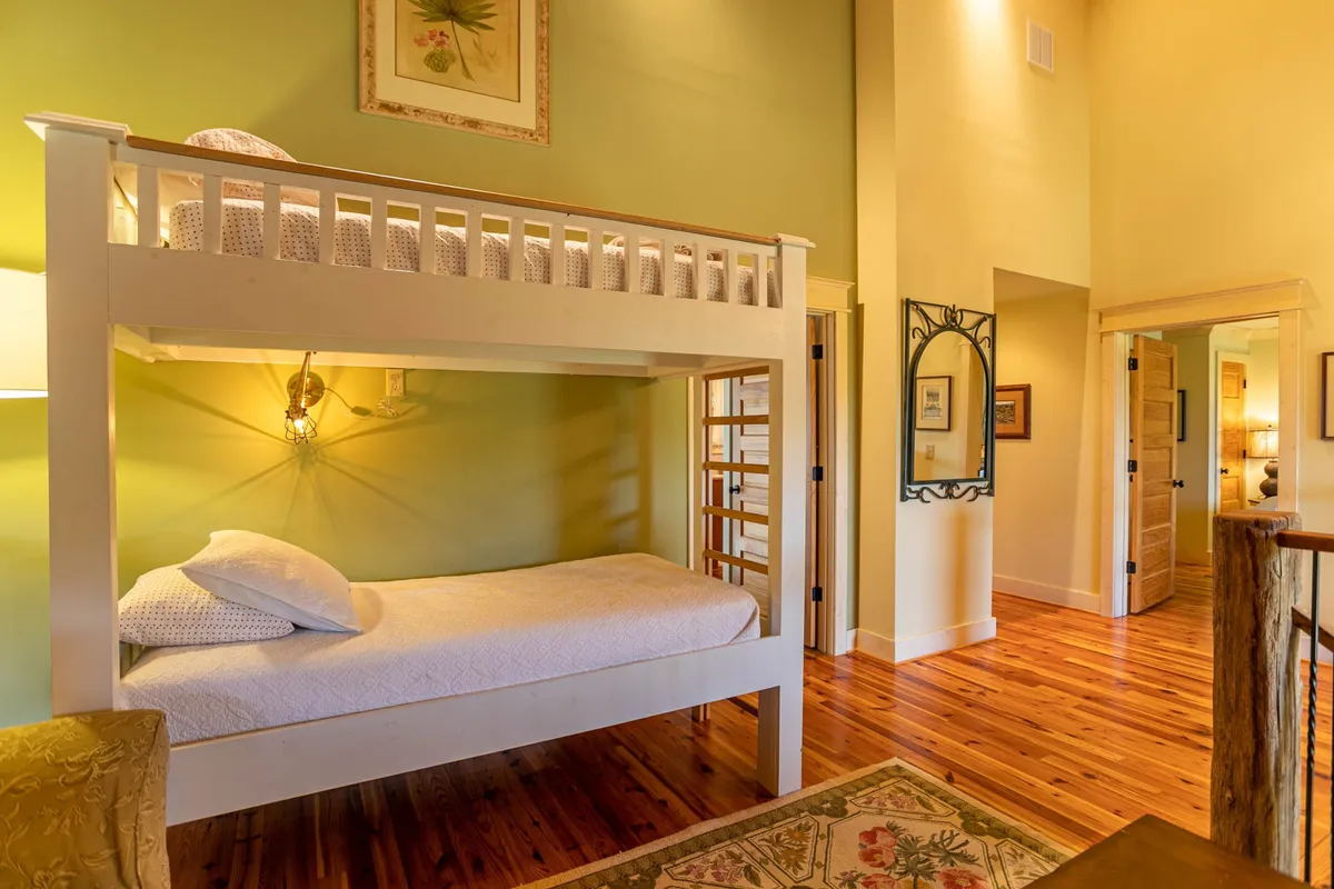 A cozy nook with a playful bunk bed, cheerful wall art, and soft lighting fixtures, set on a warm wooden floor. The space feels inviting and fun, perfect for children or teens, and evokes the versatility of the loft area for extra guests.