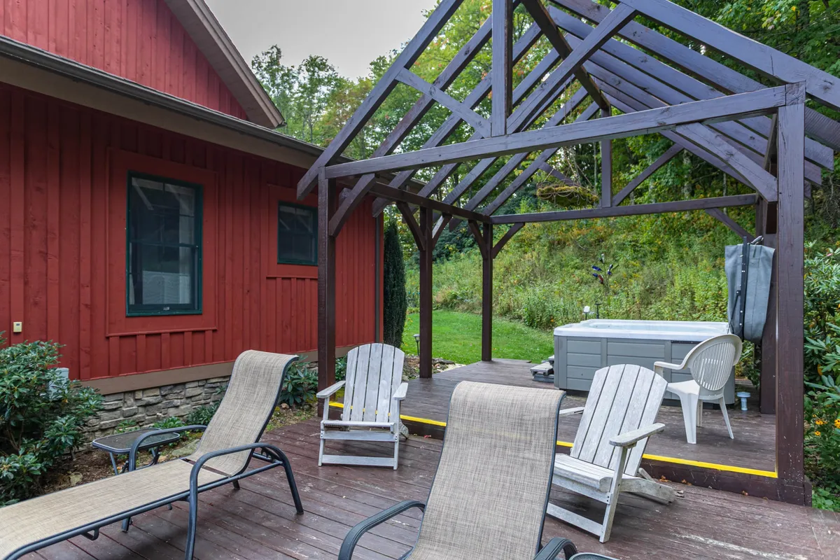 This image features a rustic wooden gazebo with a hot tub and lounge chairs, set amidst a natural outdoor landscape. The open design of the gazebo invites relaxation and socializing while offering panoramic views of the surrounding mountains and forests. The tranquil atmosphere reflects the pristine, untouched environment described in the section.