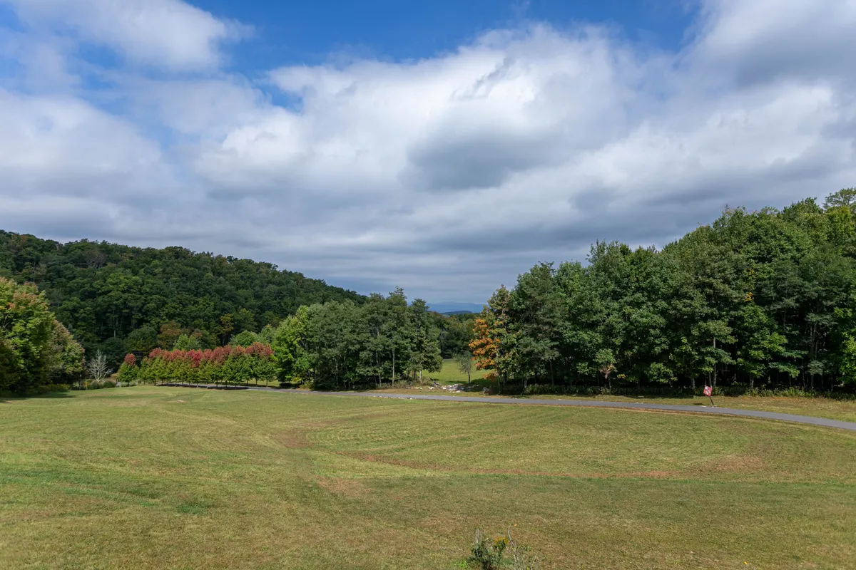 A sweeping view across rolling hills and a distant tree line under an open sky, evoking the vastness and natural beauty of the High Country. The scene suggests opportunities for hiking, nature walks, and quiet contemplation just steps from the home.